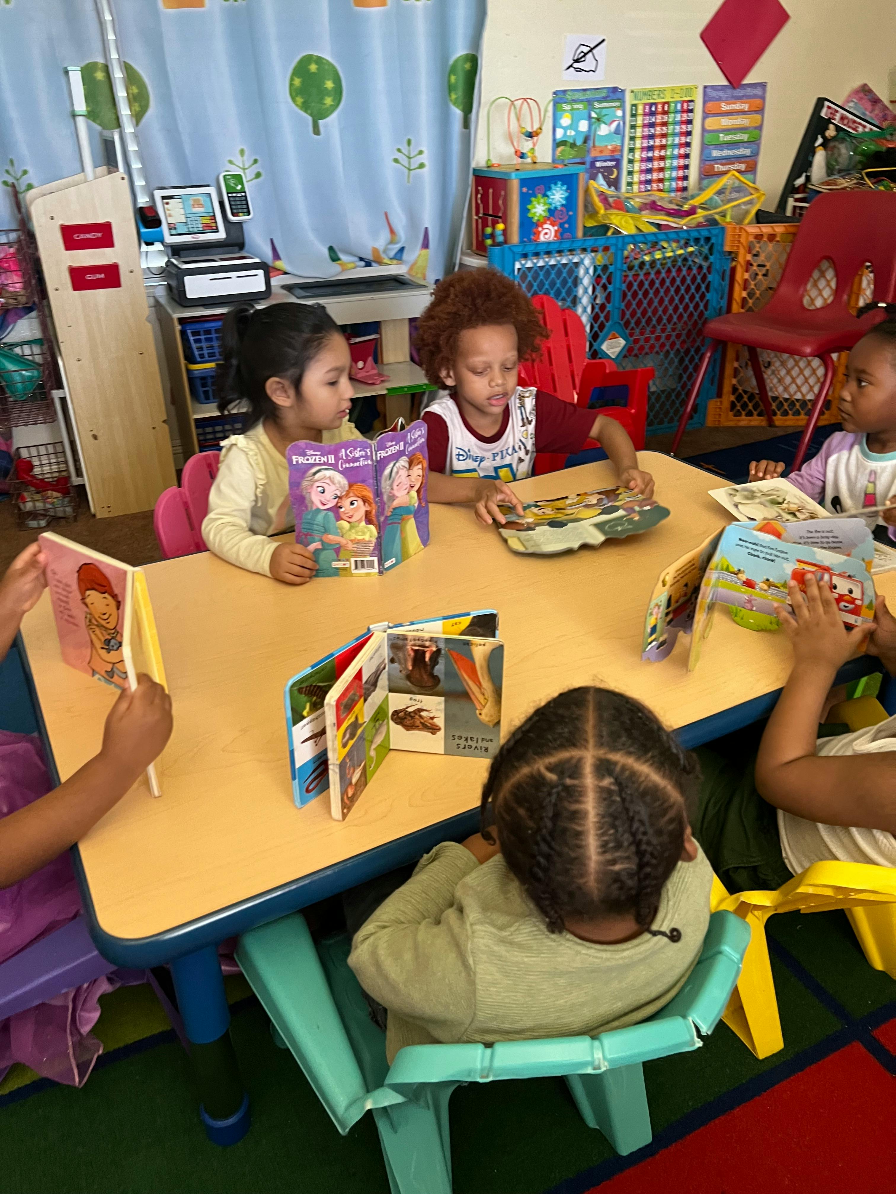 Children sitting at a table reading books in a classroom