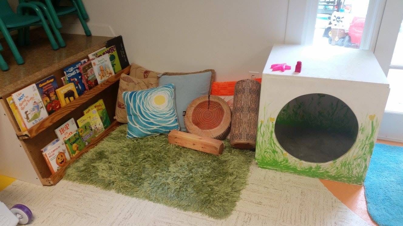 Children's reading nook with a bookshelf, pillows, and a play tunnel