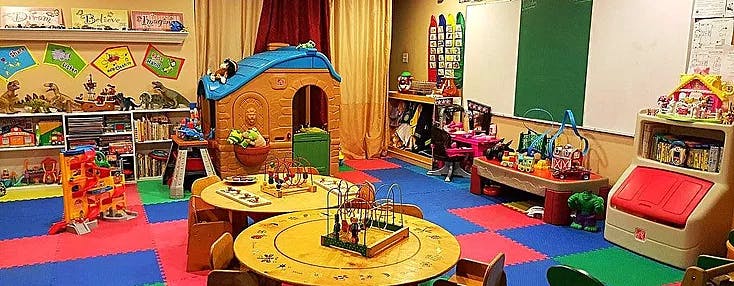 Playroom with colorful floor mats, small tables, and toys