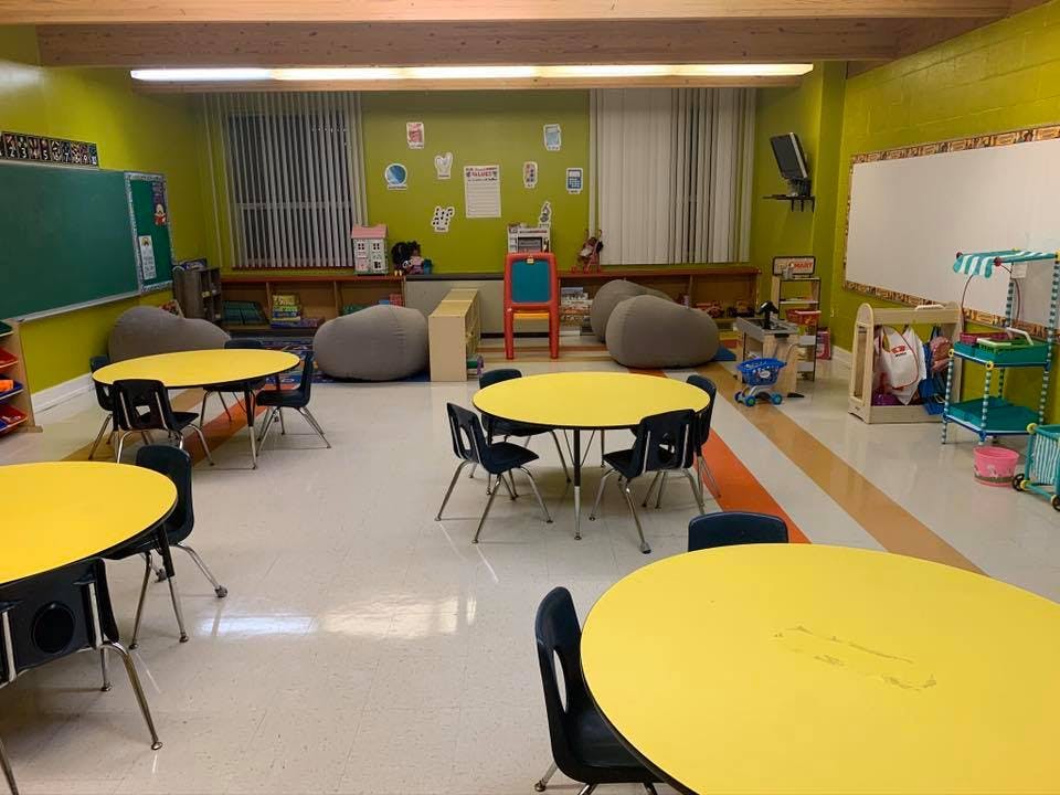 Classroom with yellow tables and chairs, beanbag chairs, and a whiteboard