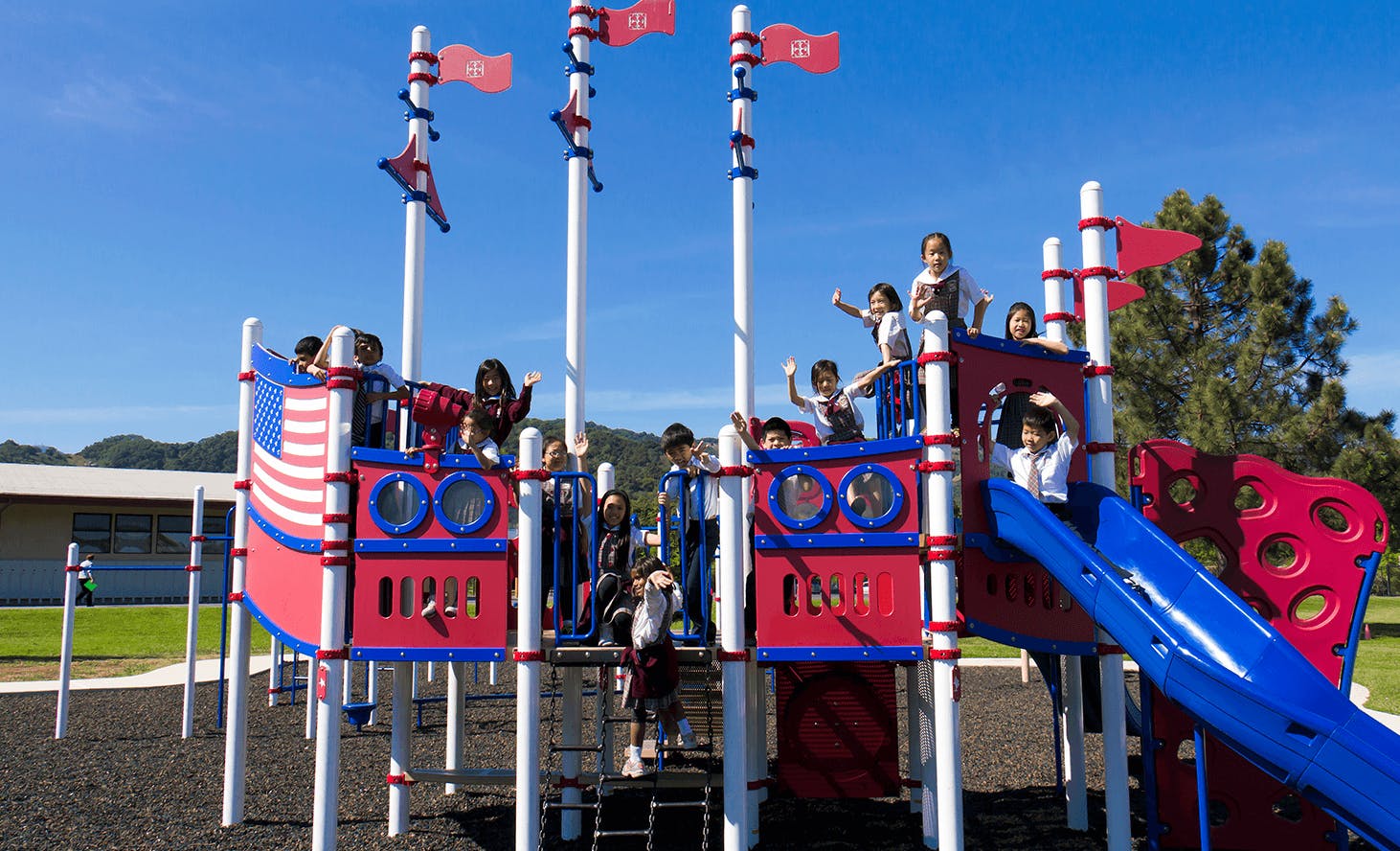Children playing on a red, white, and blue playground structure