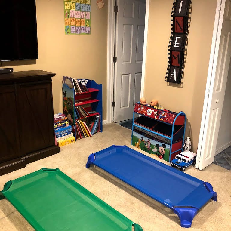 Two child cots on carpet with toy storage and books in background