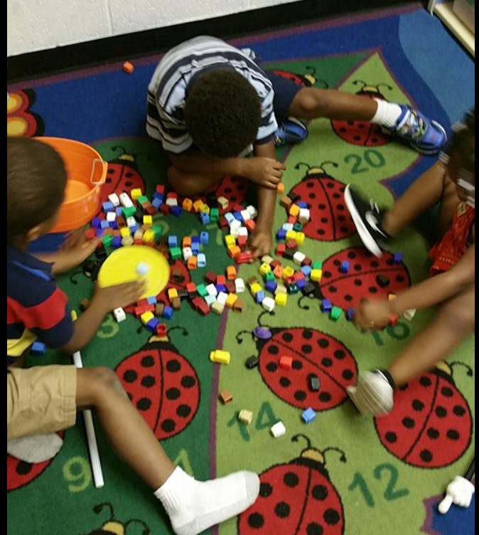 Children playing with colorful building blocks on a ladybug rug