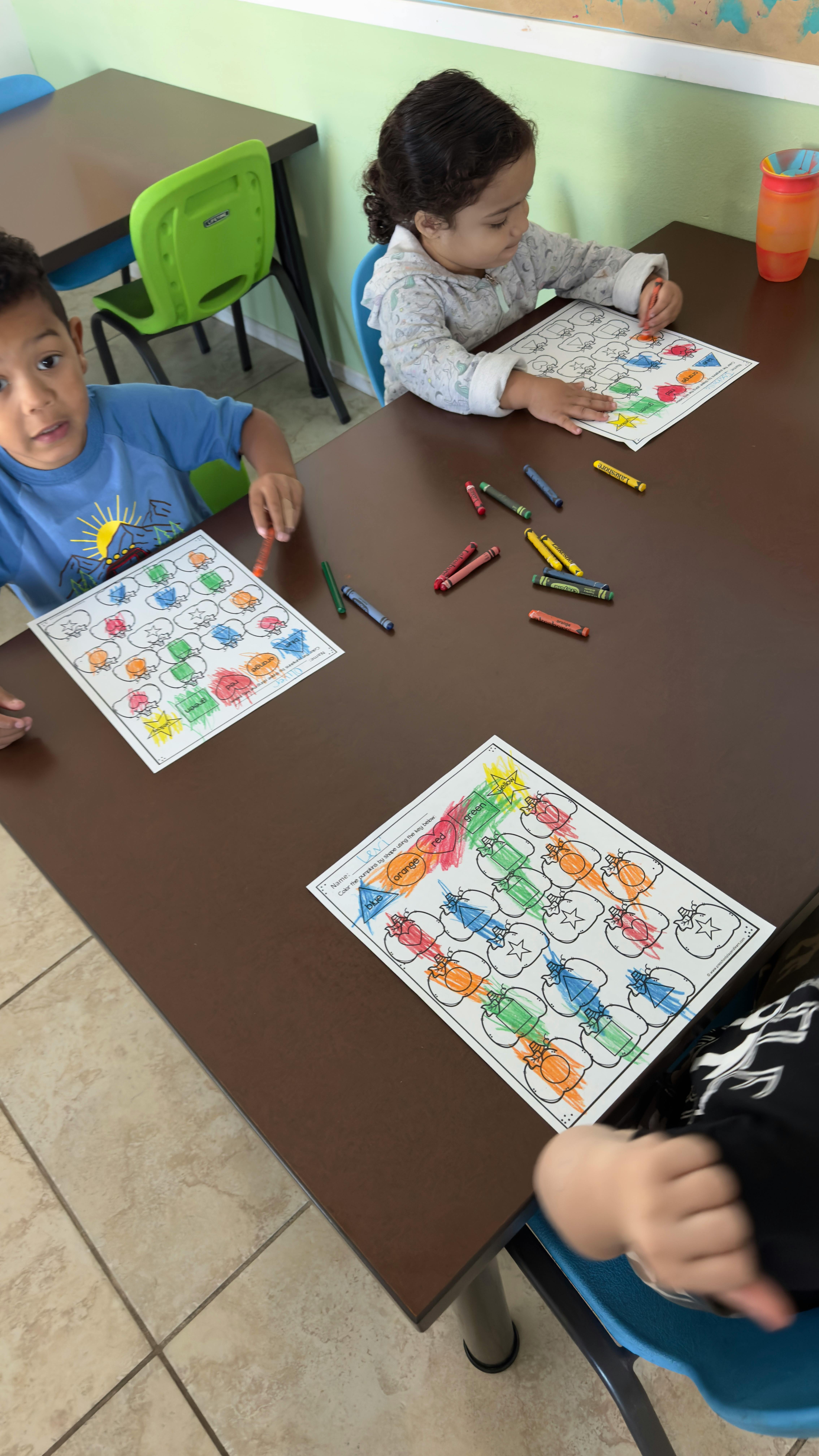 Two children coloring at a table with crayons
