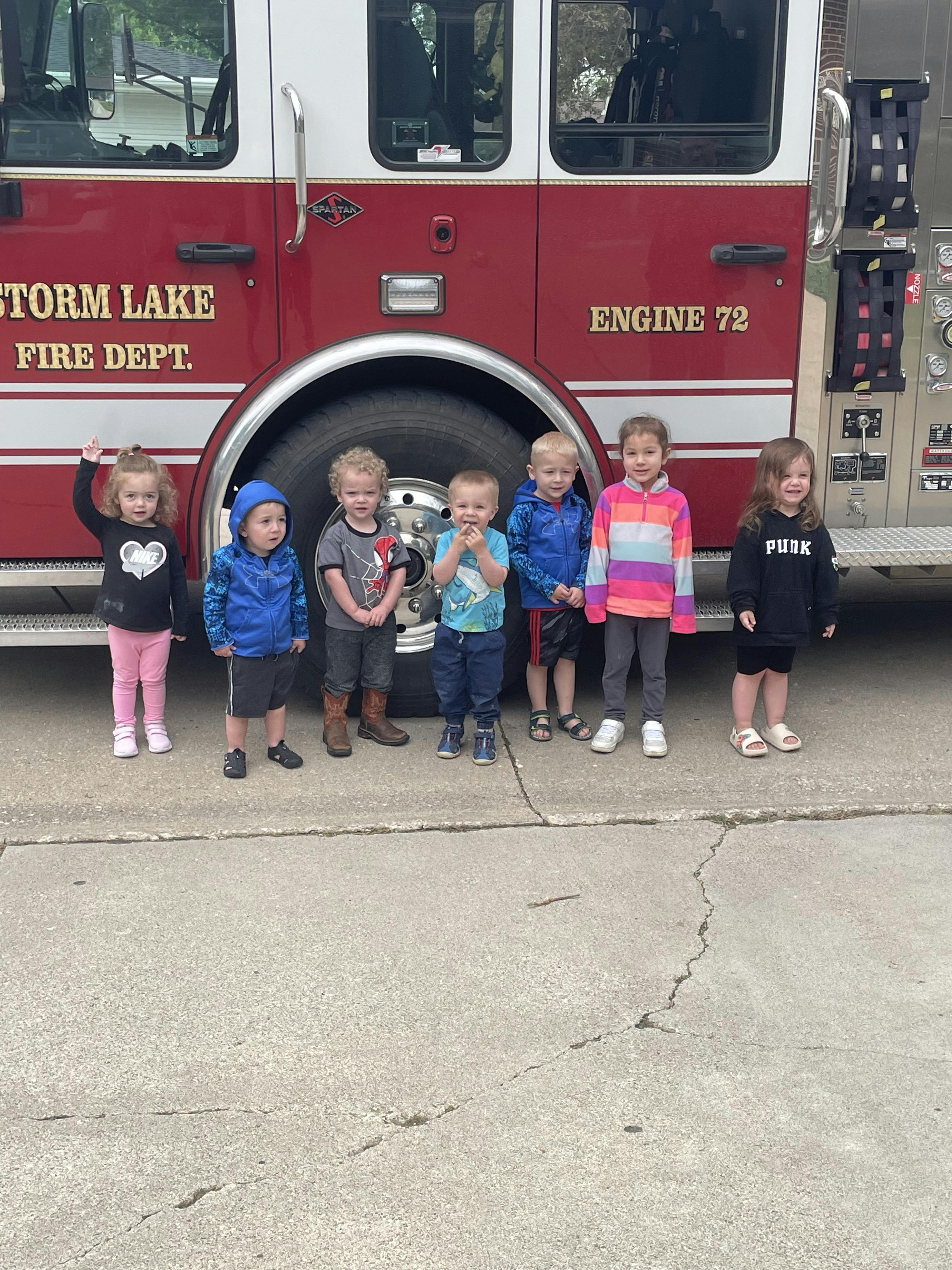 Six young children standing in front of a fire truck