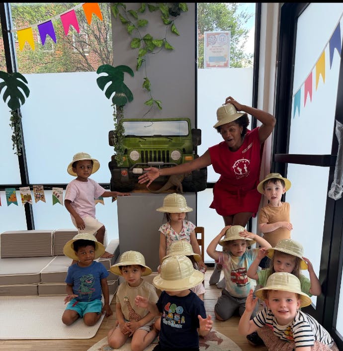 Adult and several children in safari hats, in front of a toy jeep