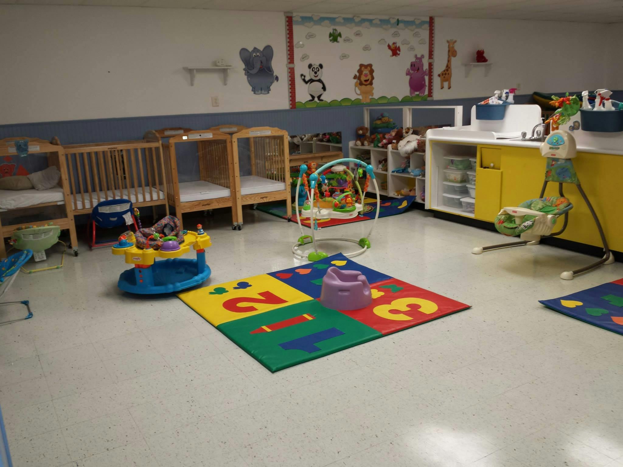 Nursery room with cribs, play mats, and baby activity centers