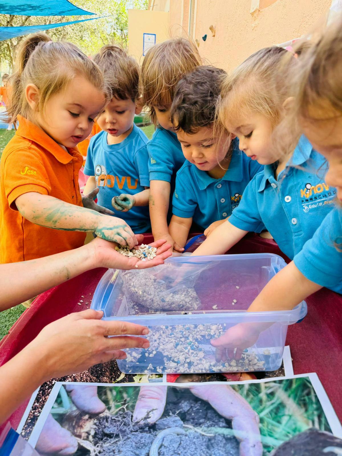 Children playing with small pebbles in a container