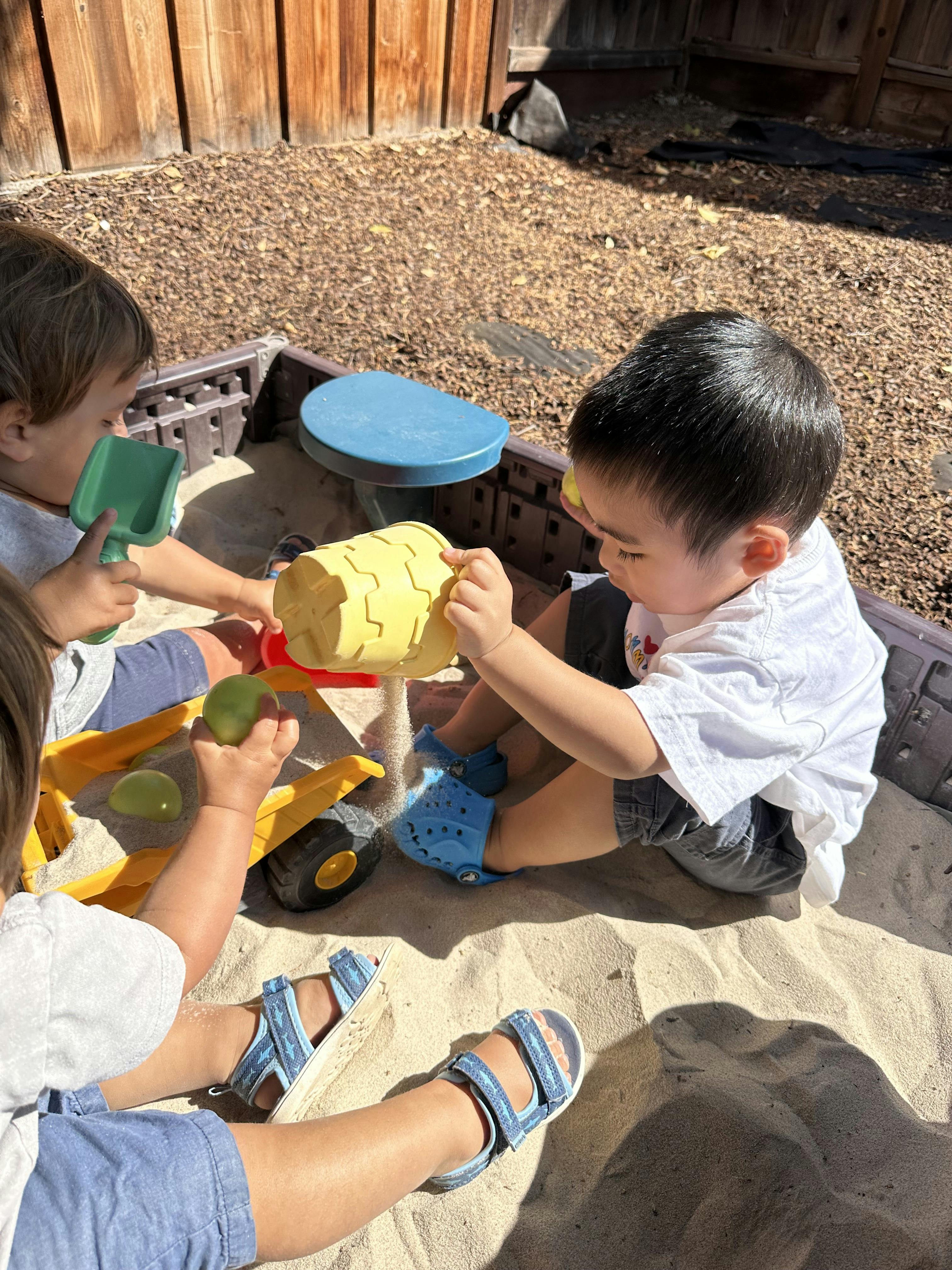 Children playing in a sandbox with toys