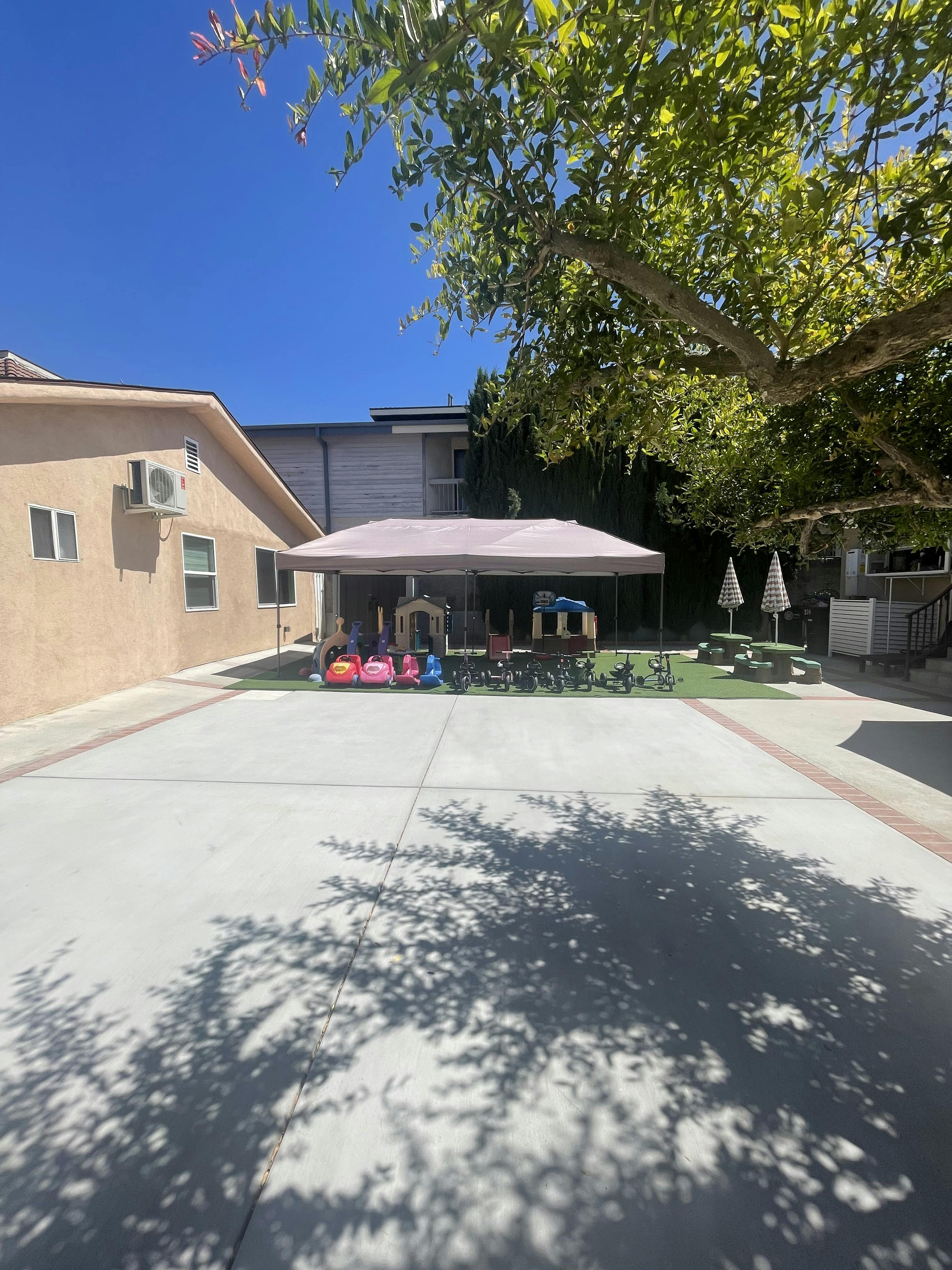 Outdoor play area with a canopy, toys, and picnic tables