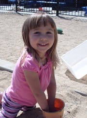 Child in a sandbox holding a bucket