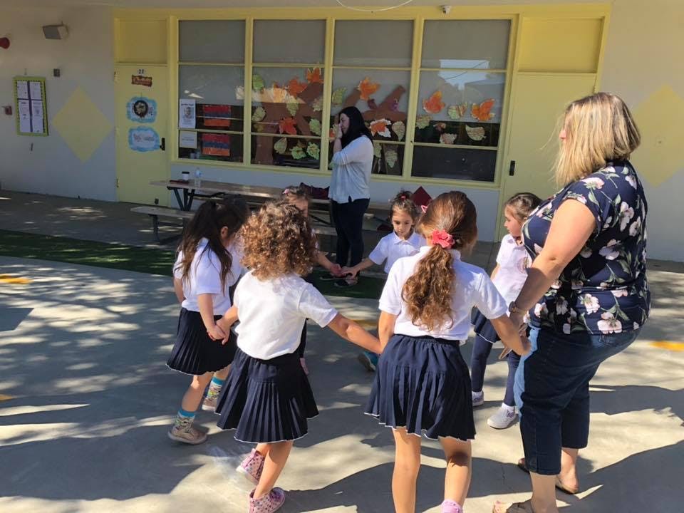 Adults and children holding hands in a circle outdoors