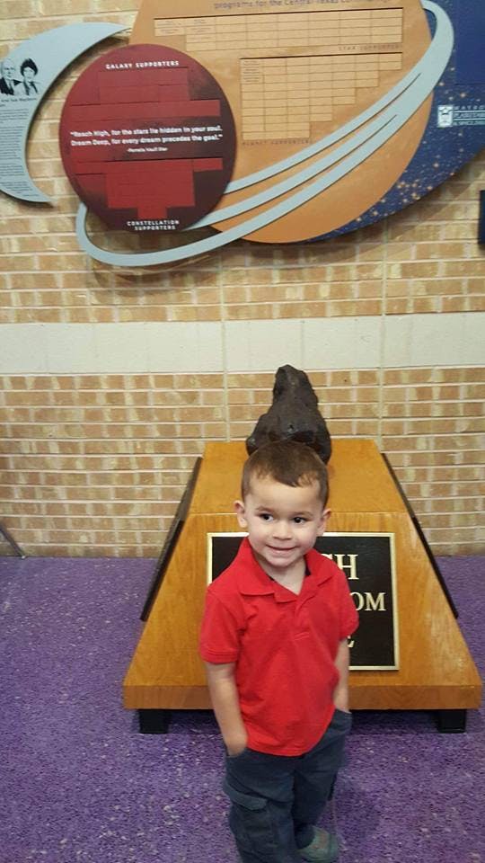 Child in a red shirt standing in front of a display