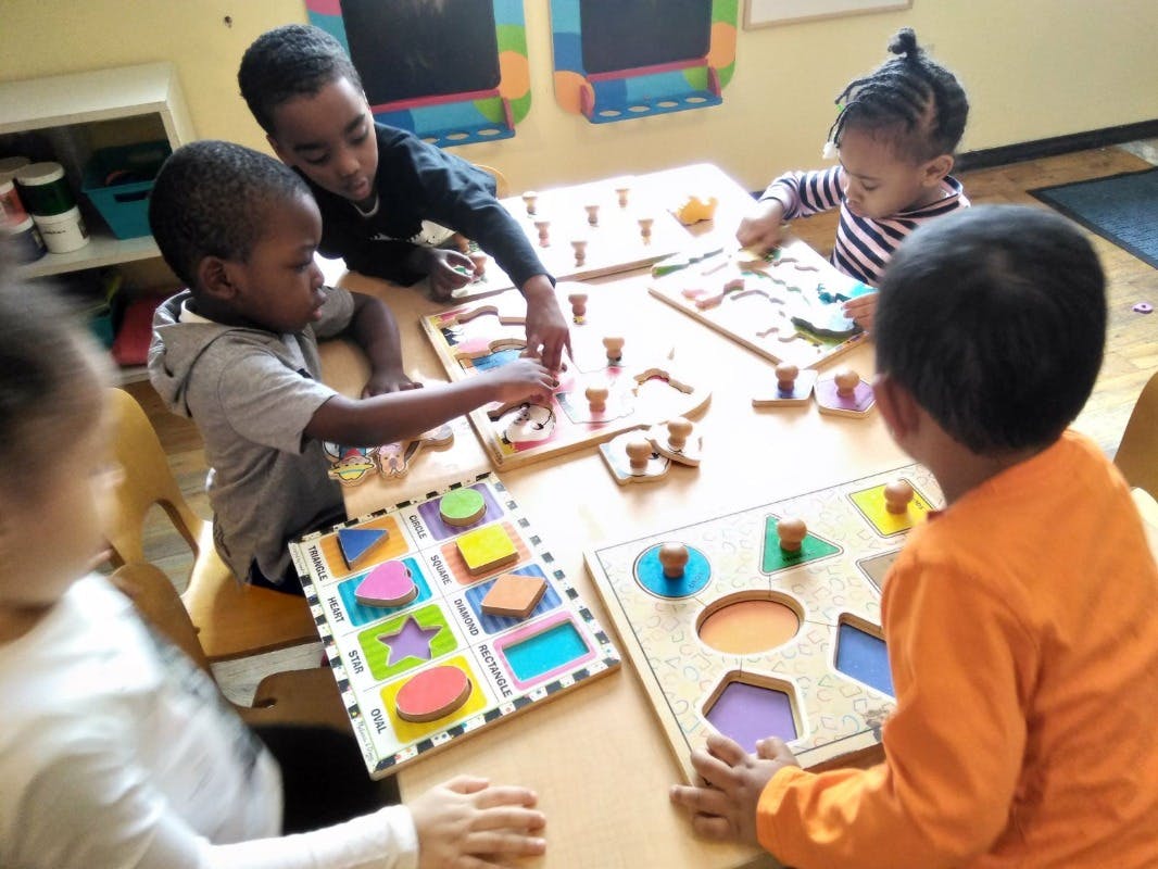 Children playing with shape puzzles at a table