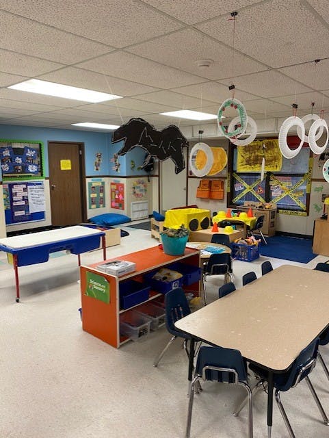 Empty classroom with tables, chairs, and colorful decorations