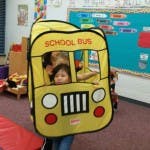 Child in a school bus costume in a classroom