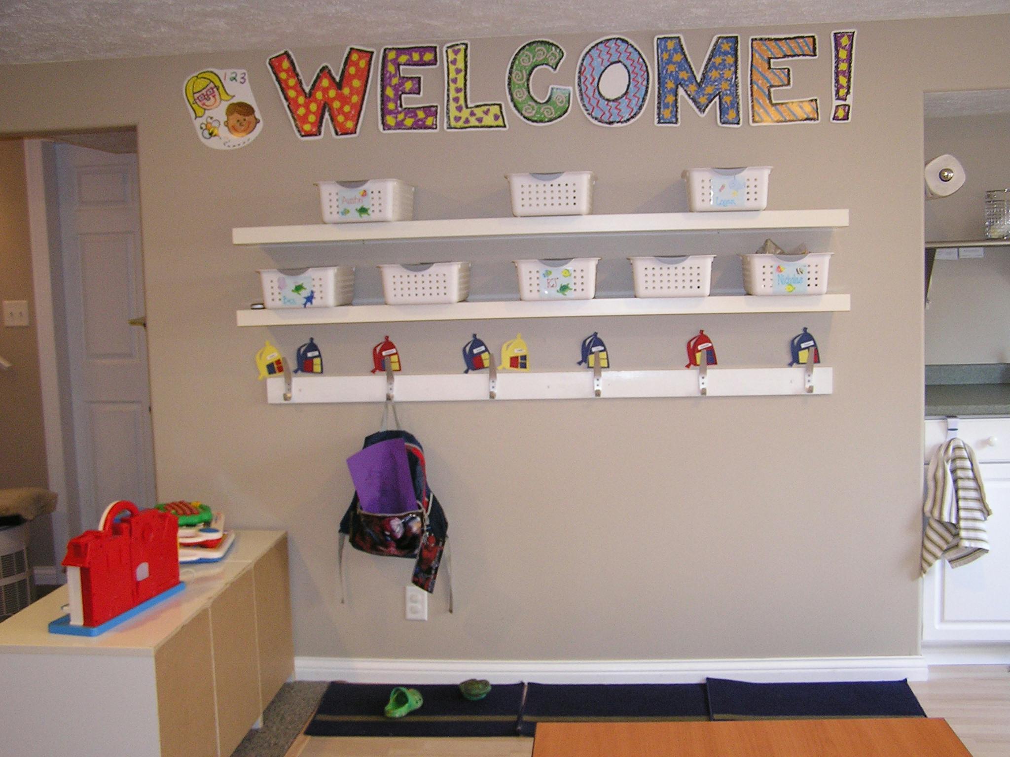 Classroom wall with WELCOME sign, shelves, coat hooks, and backpack