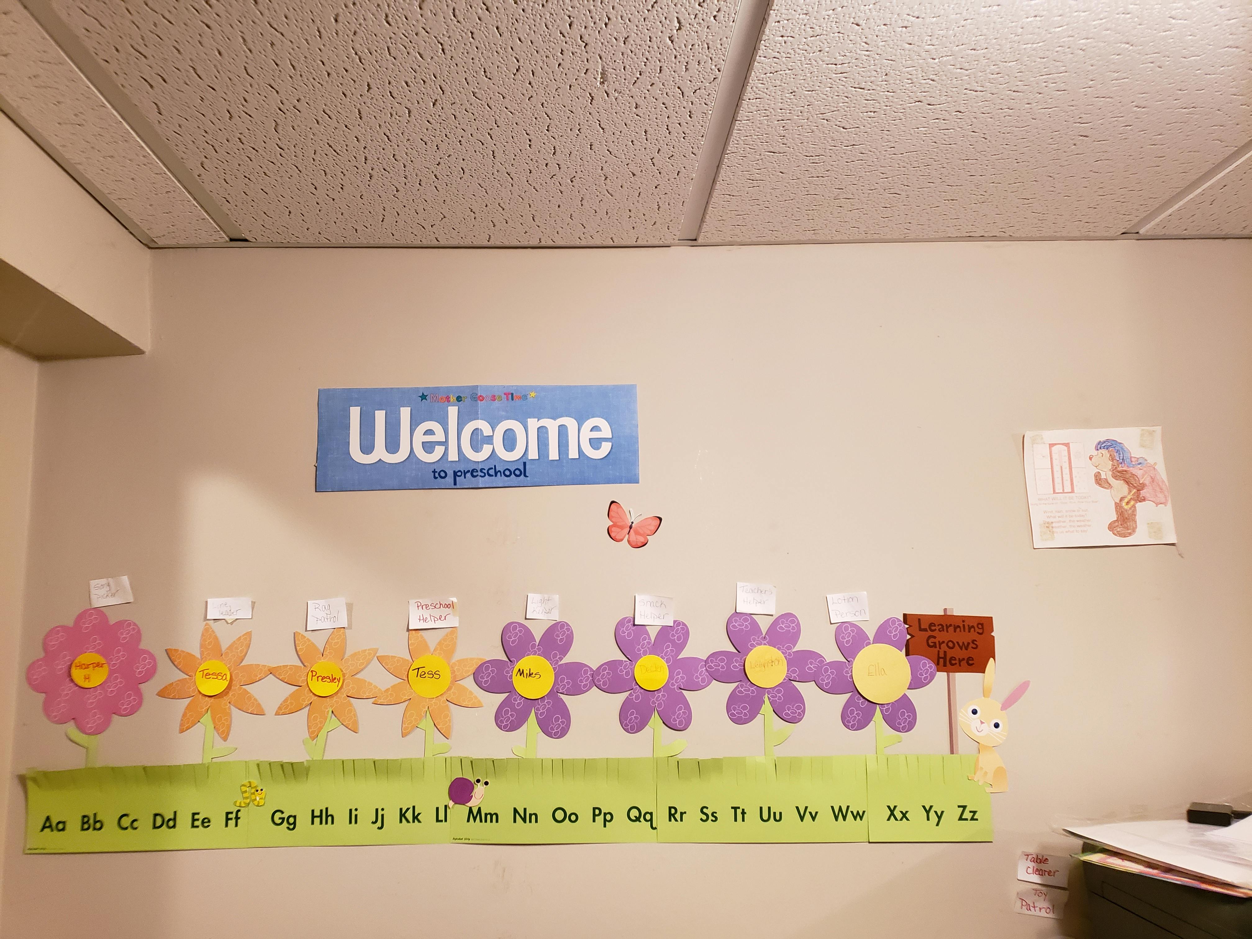 Welcome sign above flower cutouts and alphabet chart on a wall