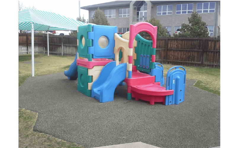 Colorful plastic playground structure with slides on rubberized ground