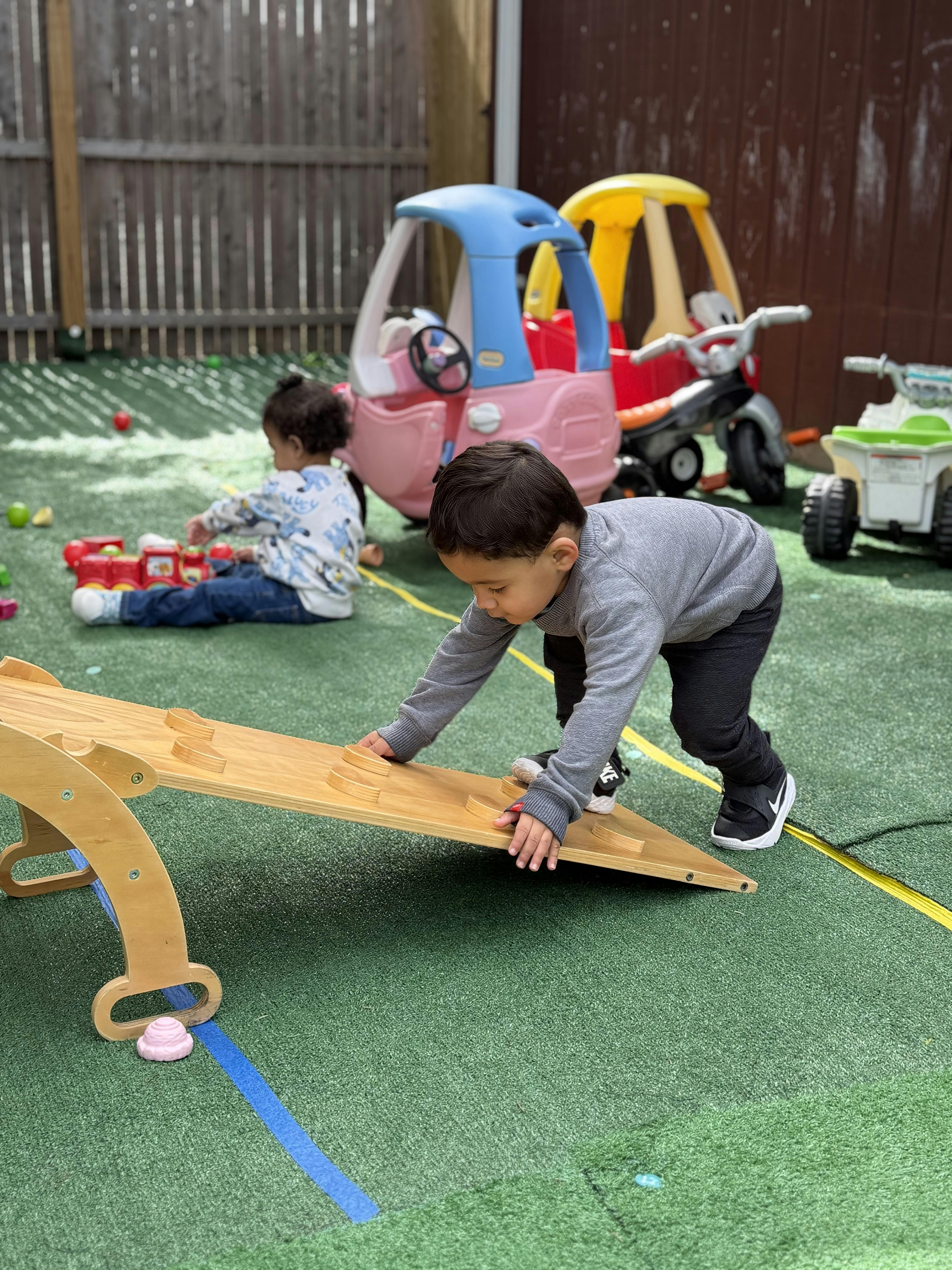 Child climbing on a small wooden ramp in an outdoor play area