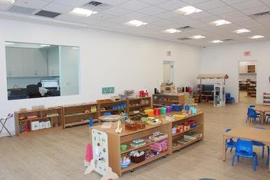 Classroom with shelves of learning materials and small tables with blue chairs