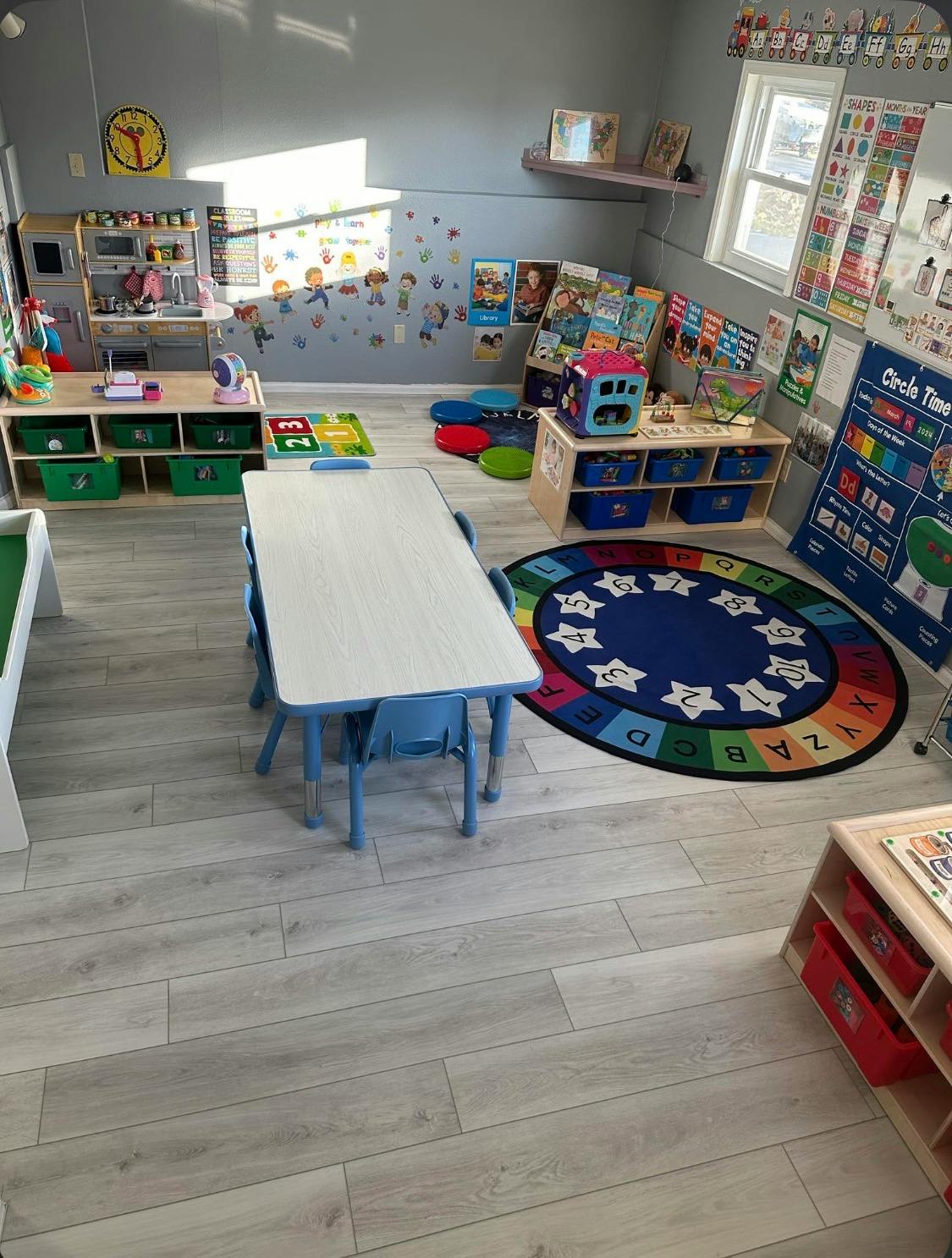 empty bright preschool classroom with tables, chairs, and play areas