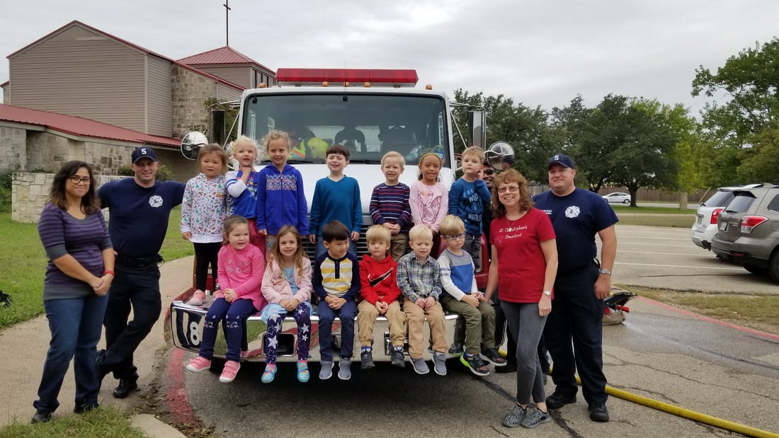 Group of children and adults posing in front of a fire truck
