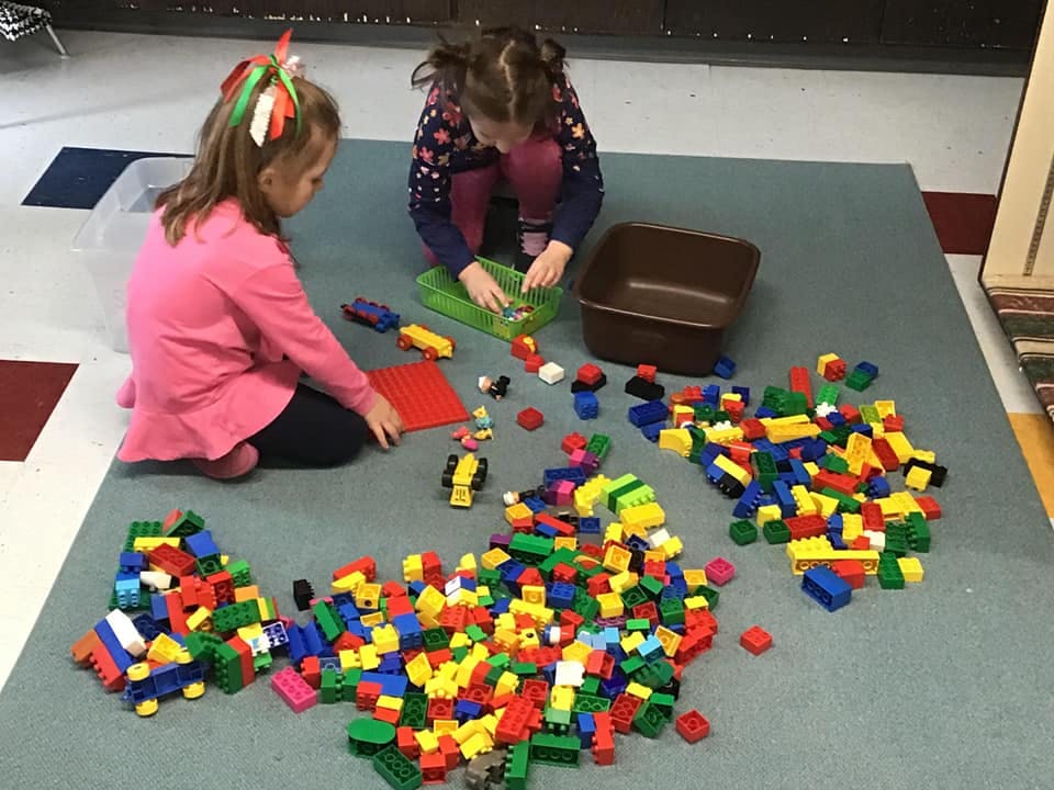 Two children playing with colorful building blocks on the floor