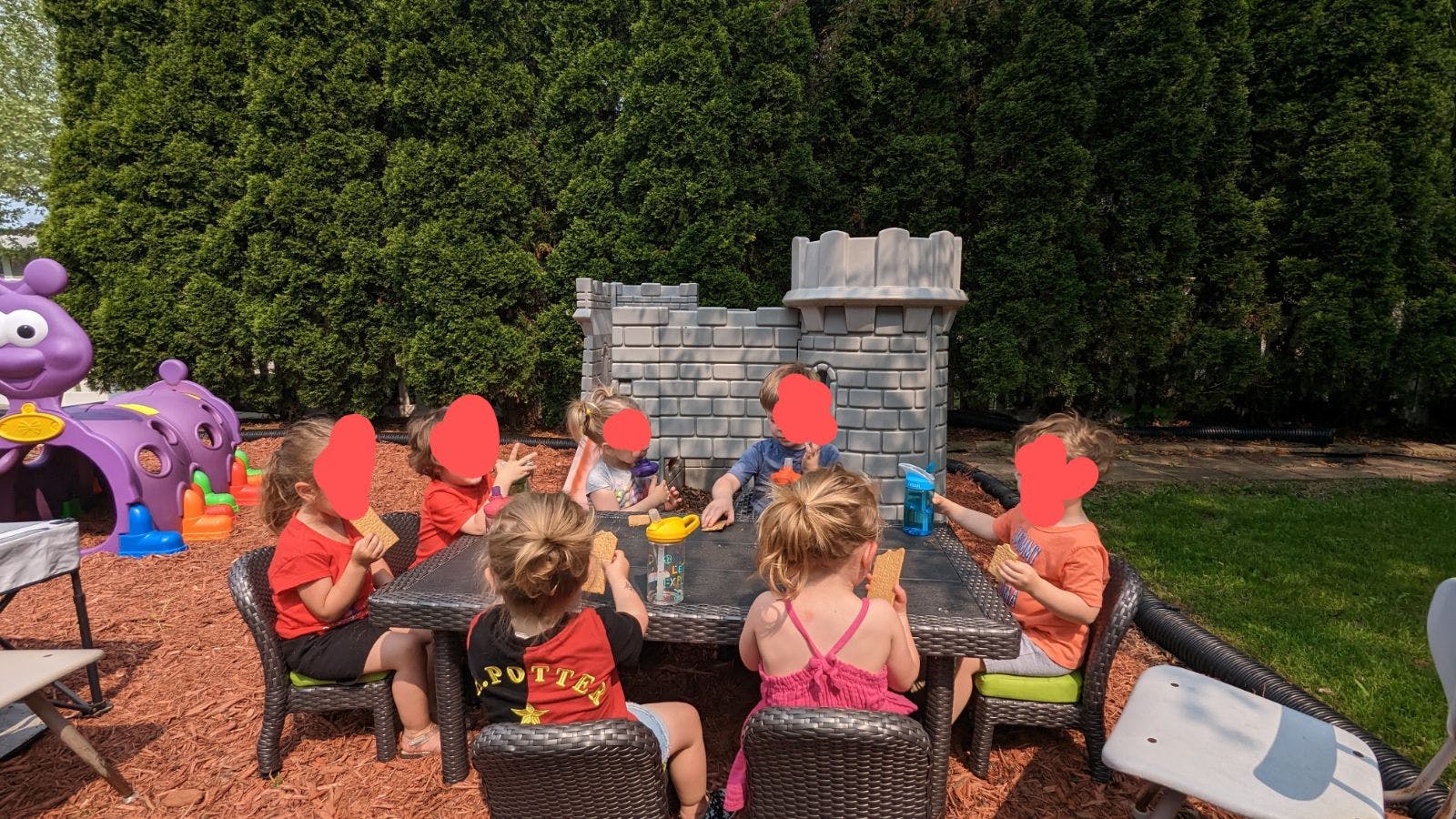 Children playing at a table with a toy castle