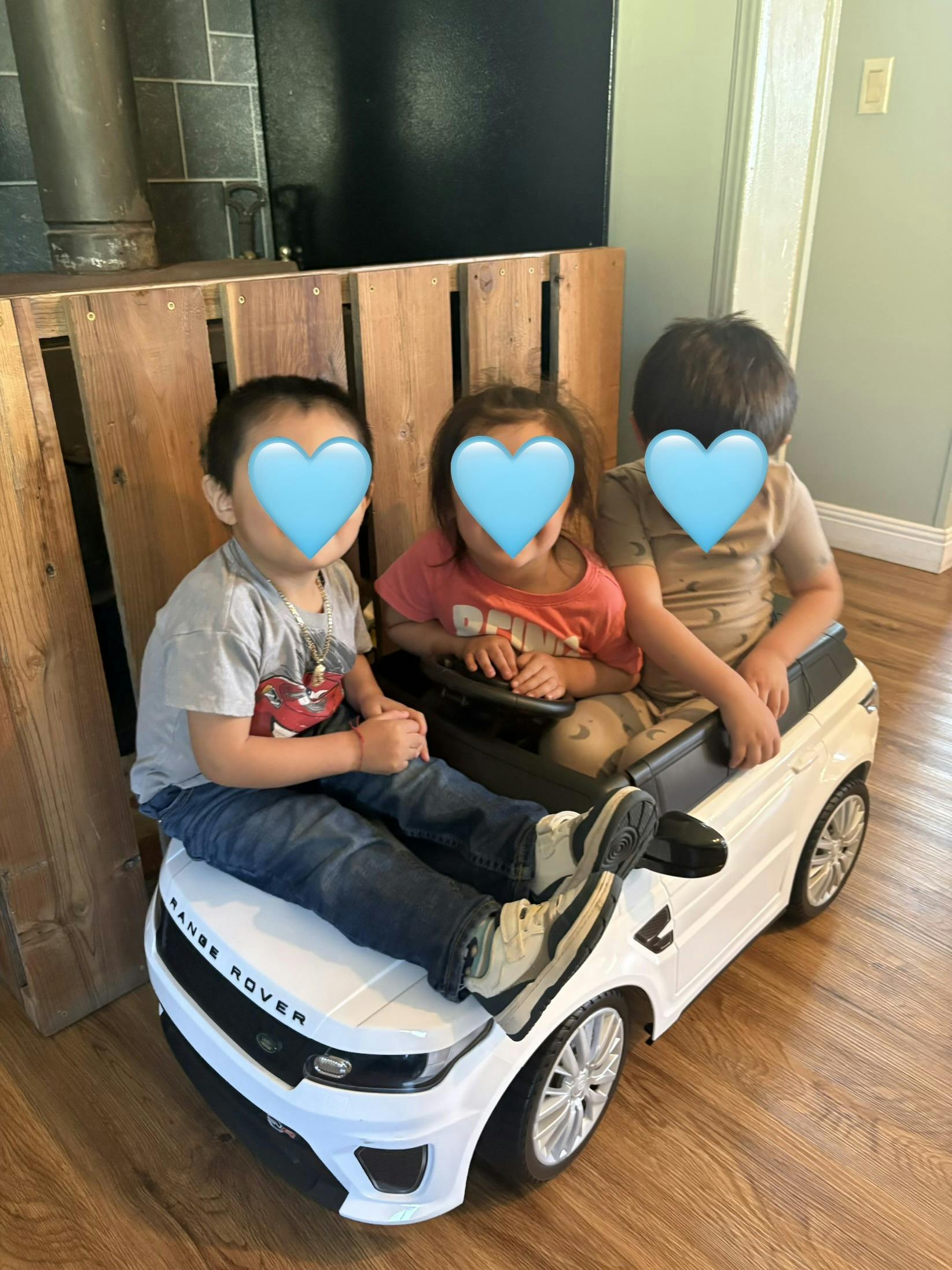 Three children sitting in a toy Range Rover vehicle