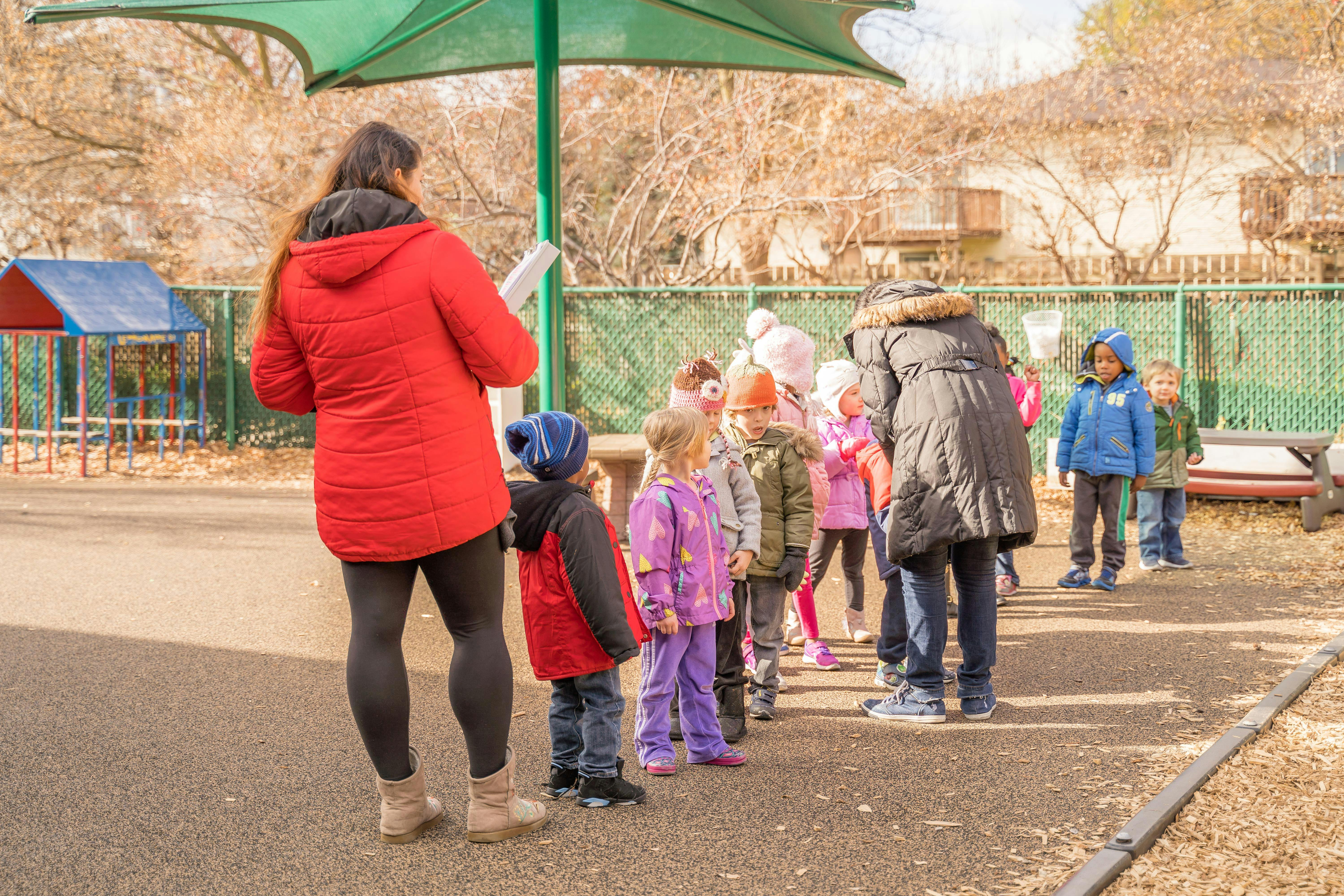 Adults supervising children in a line outdoors