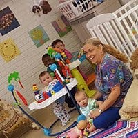 Adult and multiple children in a room with a crib
