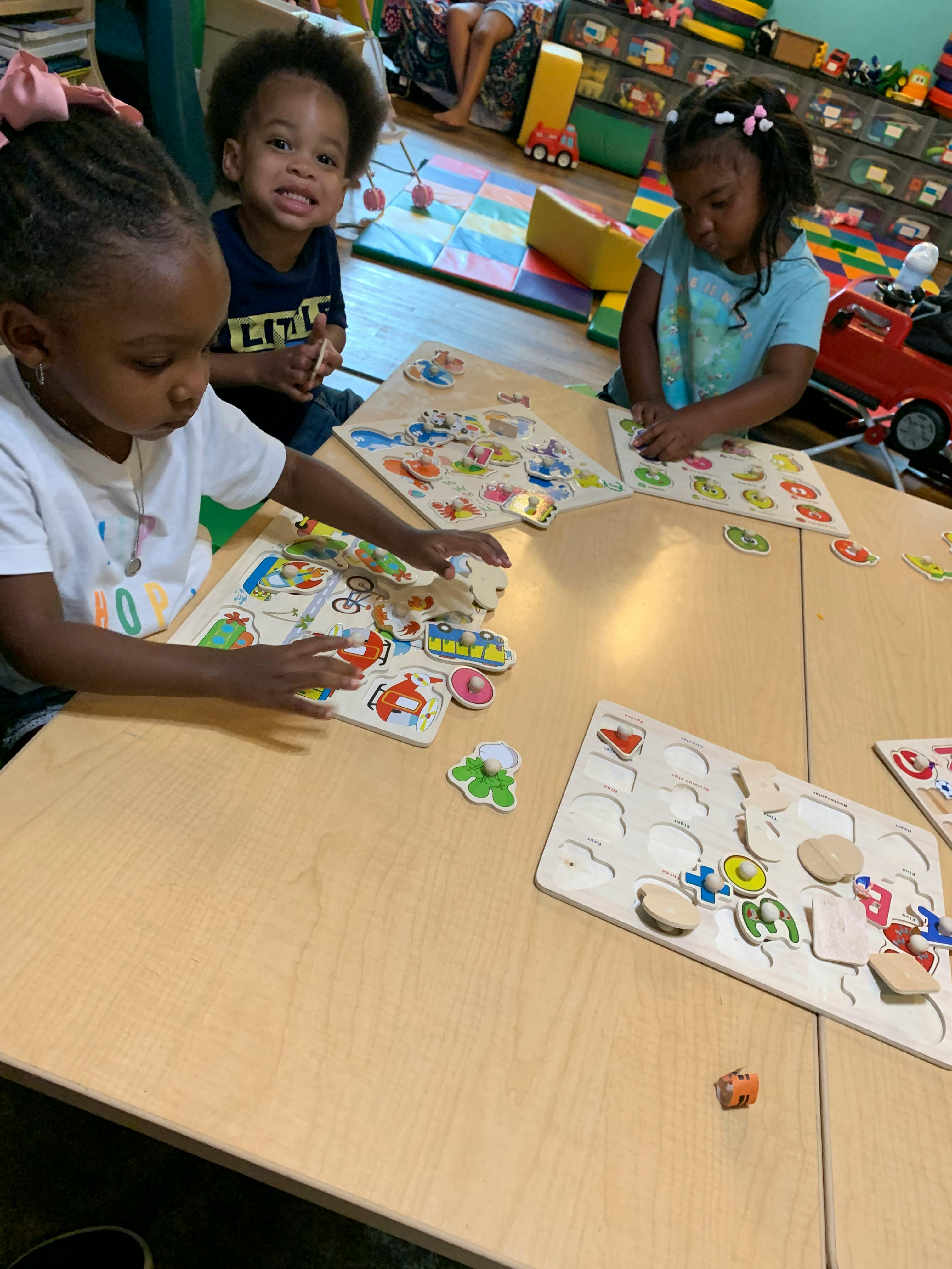 Three children playing with puzzles at a table