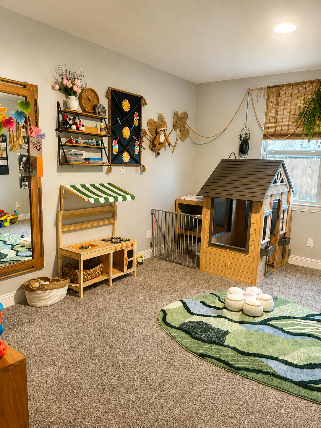 Playroom with a small wooden playhouse, a toy kitchen, and a green patterned rug