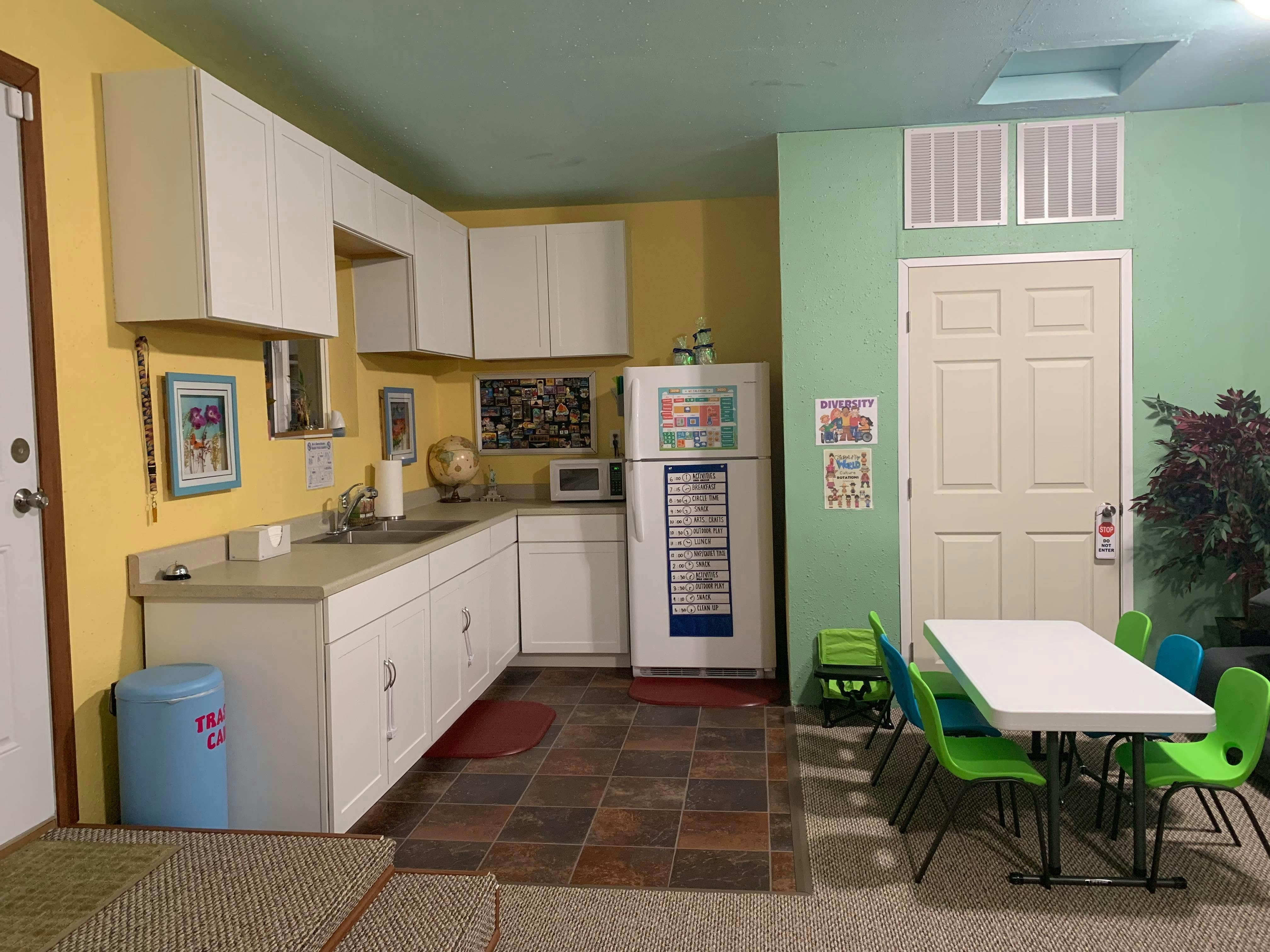 Kitchen with white cabinets, yellow and green walls, and a dining table