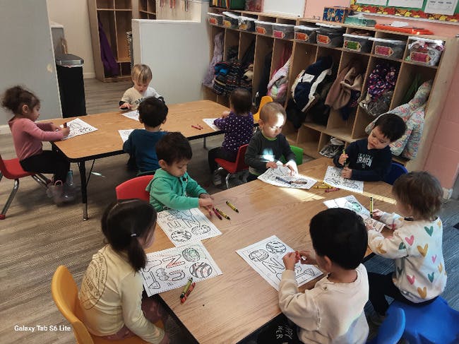 Group of children coloring at tables in a classroom