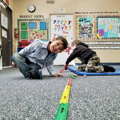 Two children playing on the floor in a classroom