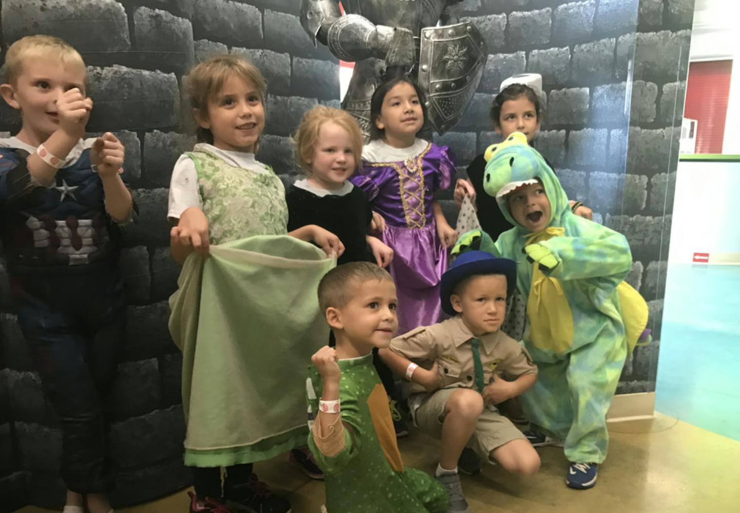 Group of children in various costumes standing in front of a castle wall