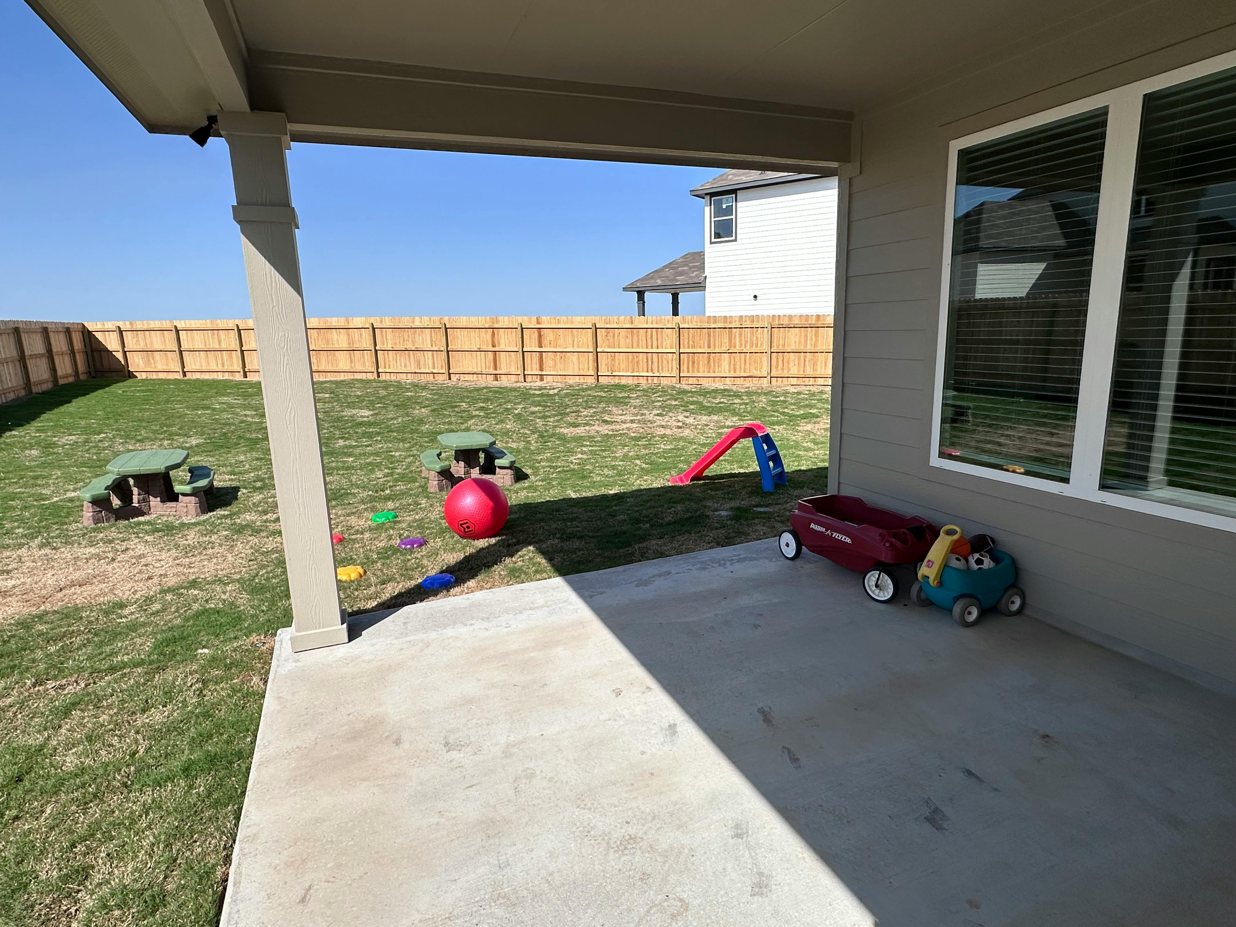 Backyard with a wooden fence, play slide, and wagon