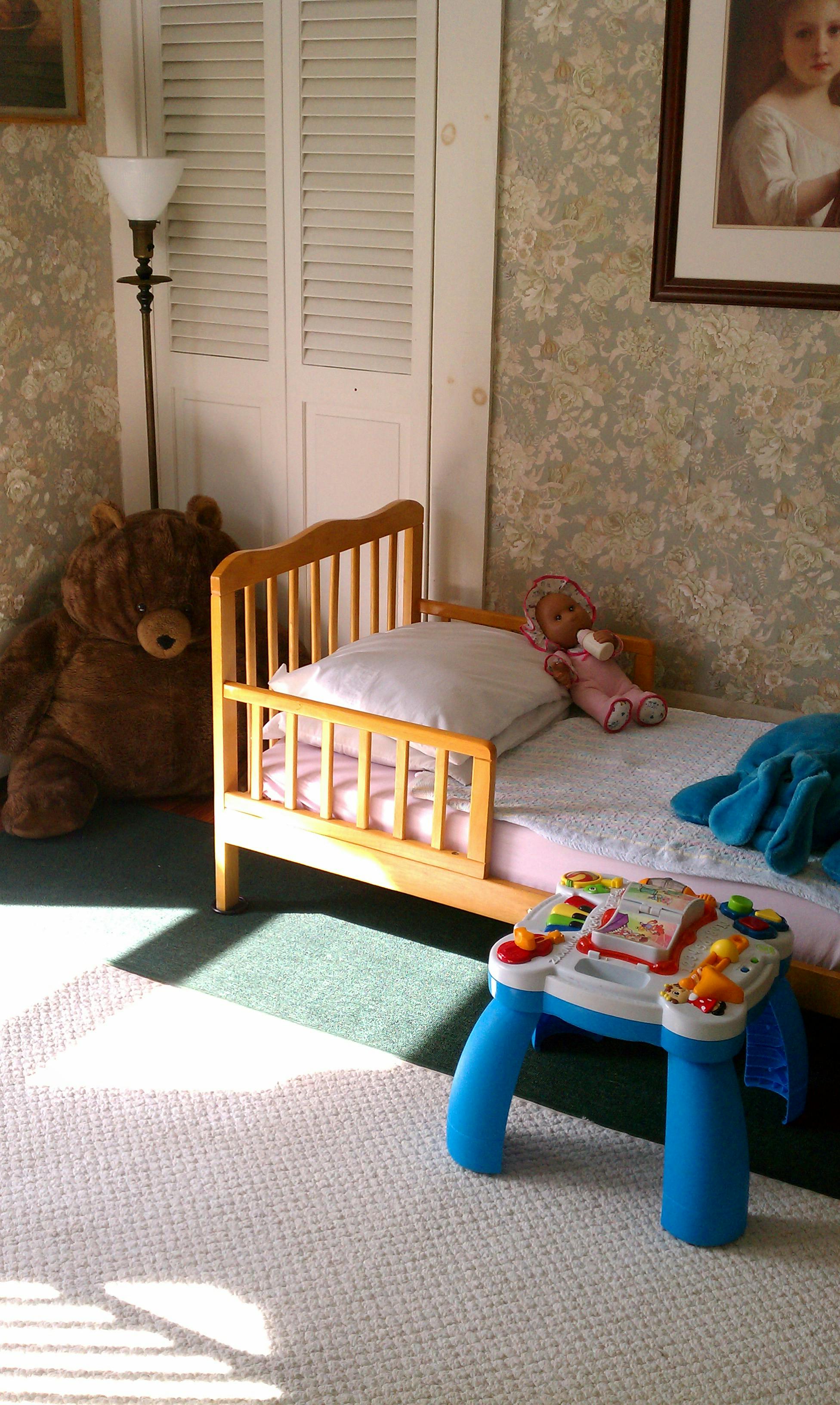 Toddler bed with a doll and a toy table next to it