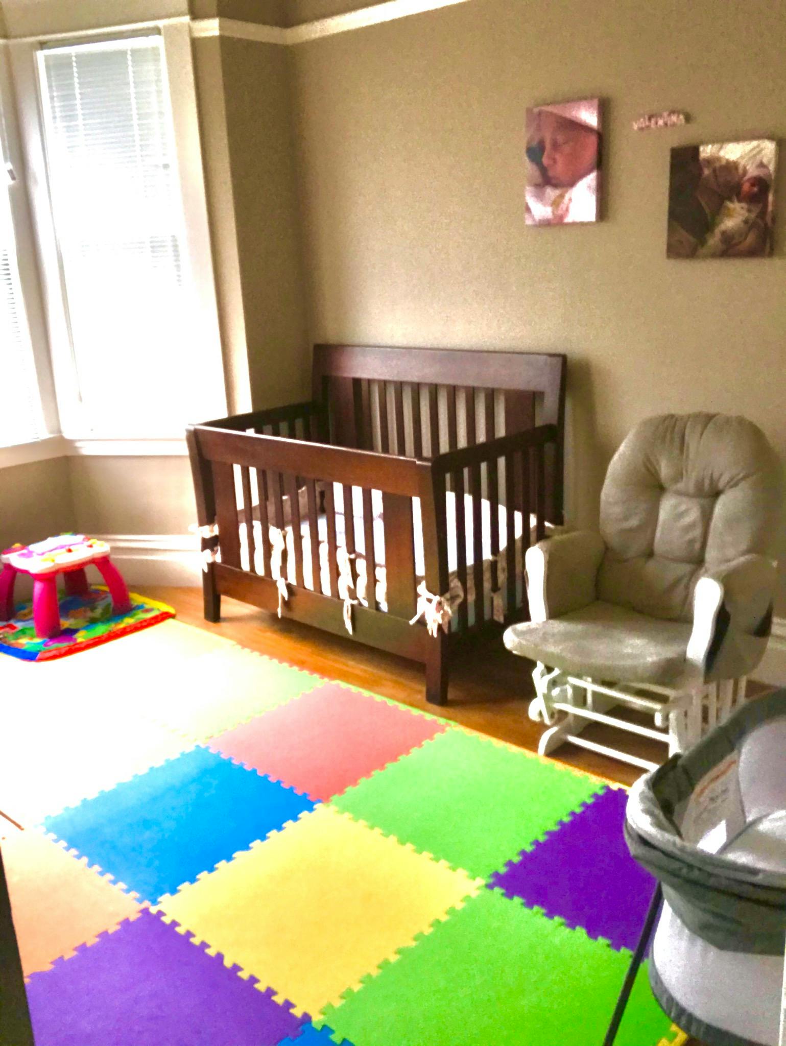 Nursery room with a crib, rocking chair, and colorful play mat