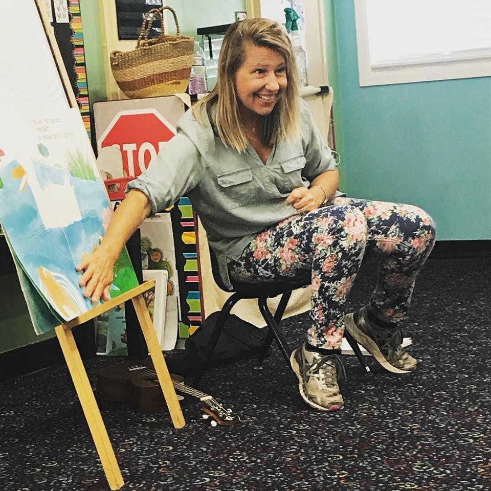 Person sitting on a chair, touching a large book on an easel