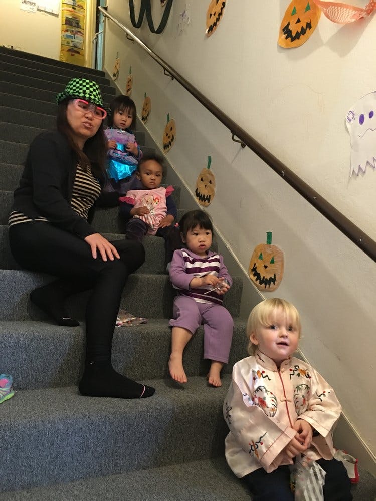 Person and children sitting on stairs decorated with pumpkins