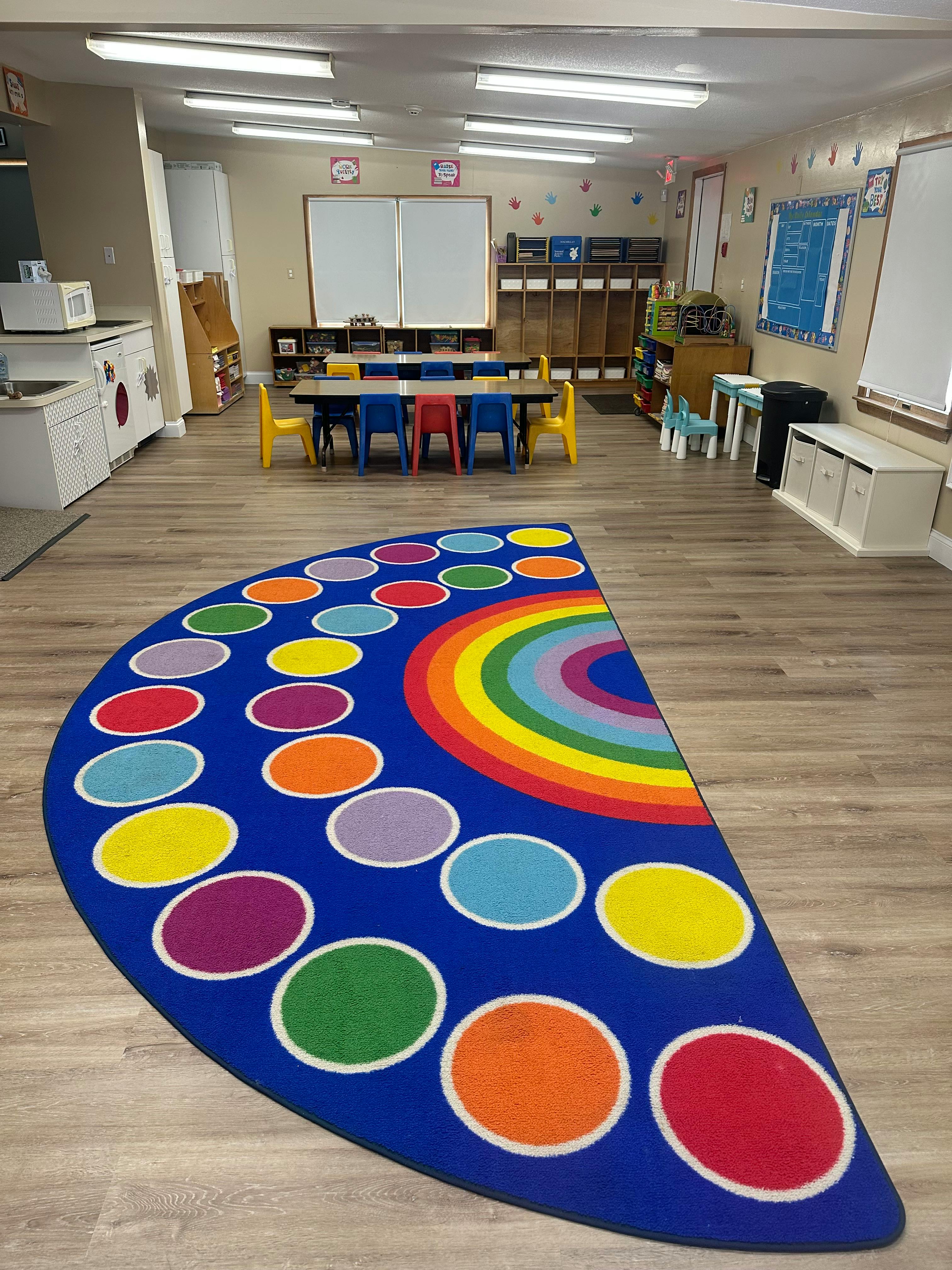 Classroom with a colorful half-circle rug and small tables and chairs