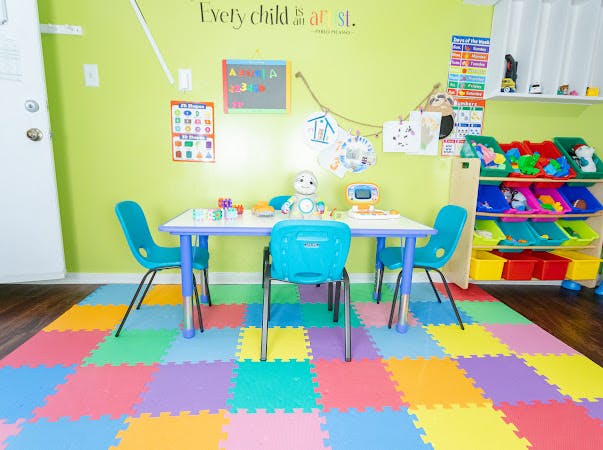 Children's classroom with small table and chairs on a colorful mat