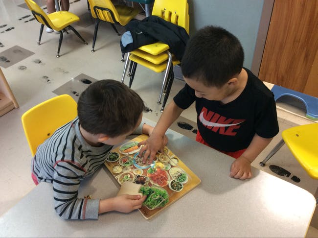 Two children playing with a puzzle at a table