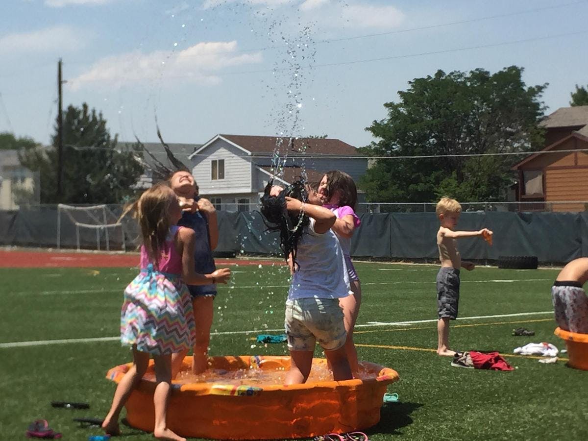 Children playing in a small pool with water spraying