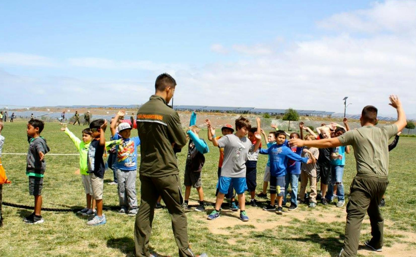 Two adults leading a group of children in an outdoor activity