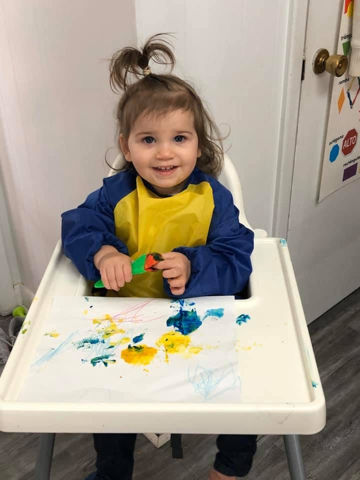 Child in high chair painting with brush