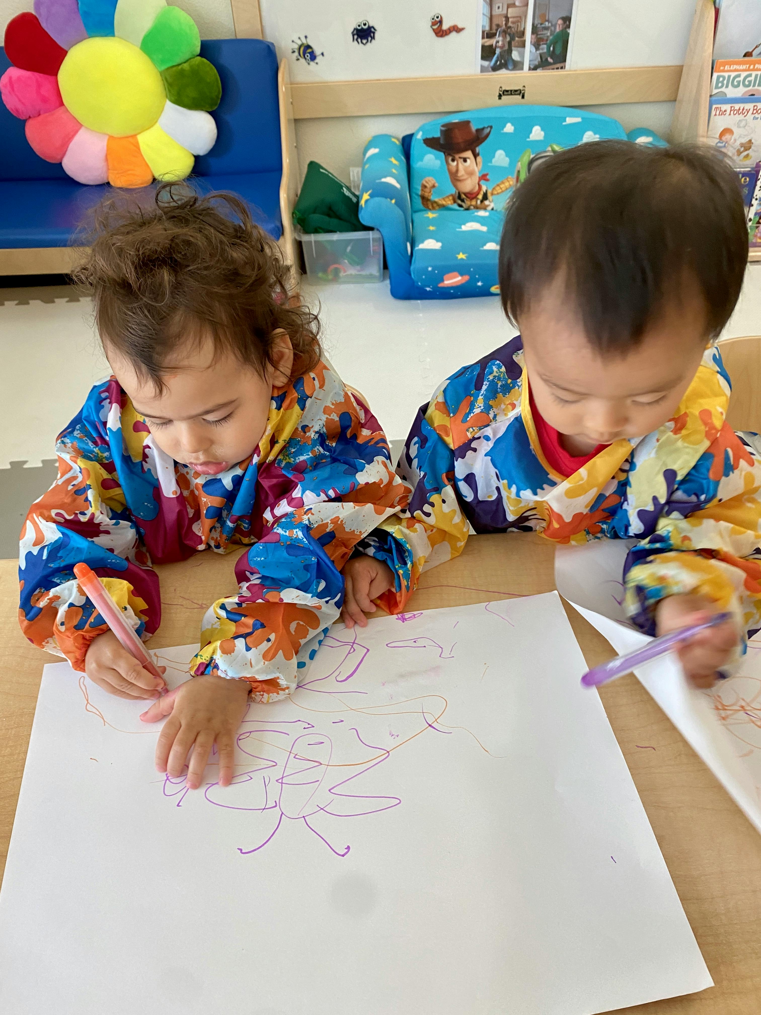 Two children drawing on paper with markers